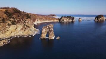 zumbido ver de un hermosa rocoso arco de natural origen en el medio de el mar video