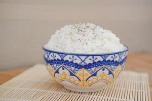 Rice in a blue bowl on a wooden table. Selective focus. photo