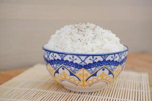 Rice in a blue bowl on a wooden table. Selective focus. photo