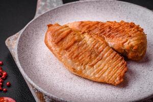 Delicious fresh grilled chicken fillet with spices and herbs on a dark concrete background photo