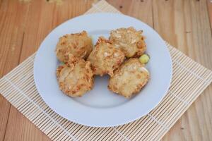 Bakwan sayur or vegetable fritter, Indonesian snack made from flour, cabbage, carrots and bean sprouts, served with chili photo