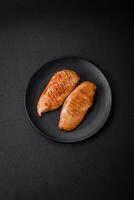 Delicious fresh grilled chicken fillet with spices and herbs on a dark concrete background photo