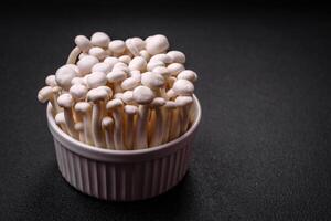 Small white edible beech mushrooms with salt and spices on a plain background photo