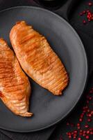 Delicious fresh grilled chicken fillet with spices and herbs on a dark concrete background photo