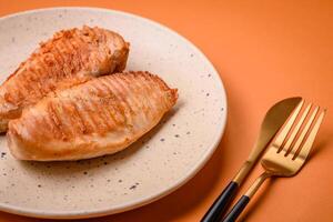 Delicious fresh grilled chicken fillet with spices and herbs on a dark concrete background photo