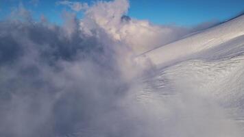 aereo Visualizza di un' montagna attraverso nuvole coperto nel glaciale crepe a tramonto. video