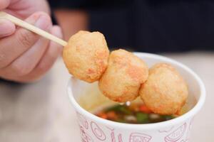 Fried fish balls with sweet and sour sauce on wooden chopsticks photo