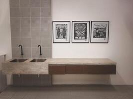 A beautiful sink  with three picture on the white wall photo