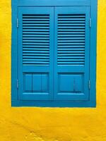 Blue window isolated  on the background of a yellow ragged wall. photo