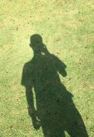 A shadow in the form of a human body with grass texture background photo