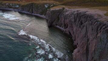 Aerial view of beautiful sea stack and dark cliffs in sunset. Calm seascape video