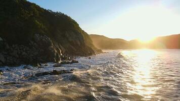 Aerial. waves at dawn lapping against a rocky shore and raising splashes video