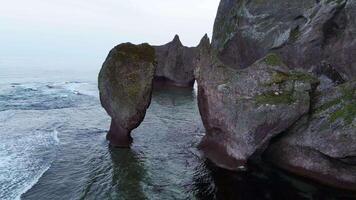 Aerial view of beautiful sea stack and dark cliffs in sunset. Calm seascape video