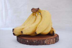 manojo de bananas en un de madera estar en un blanco antecedentes. foto