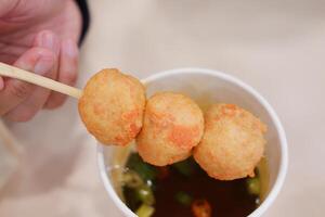 Fried fish balls with sweet and sour sauce on wooden chopsticks photo