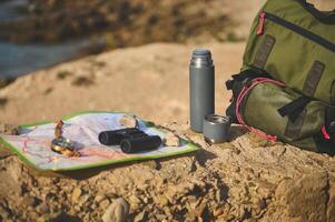 Still life backpack and thermos flask on the cliff against Atlantic ocean background while waves break on the headland. photo