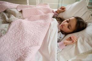 auténtico retrato de un caucásico pequeño niño niña dormido en el cama foto