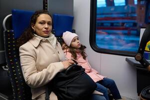 Beautiful family, mother and daughter sitting by passenger window in a high speed train commuting from one city to other. photo
