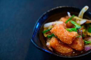 Spicy Salmon Salad on black background, Thai food photo