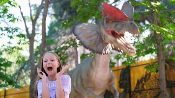 A child screams at the sight of a dinosaur. Teenage girl in dinopark. photo