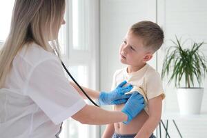 el médico escucha a el respiración de un pequeño chico mediante un estetoscopio. pediatra con estetoscopio escucha a el livianos de un niño con bronquitis y tos foto