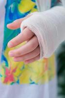 Close-up of a broken arm of a child in a cast. The girl holds her hand bent photo