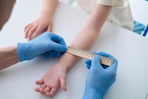 A male doctor makes an important Mantoux test on a child. The doctor measures the Mantoux test with a ruler for a little boy photo