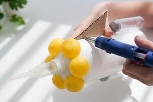 paso a paso instrucciones para haciendo artesanía desde improvisado materiales hecho a mano a colegio arte cohete para el día de cosas de cosmonautas. el niño es pegar partes a un el plastico botella. paso 11 foto