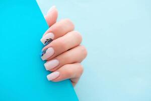 Beautiful female hands with manicure on a blue background. Stylish nail design. Summer manicure with a blue pattern on the nails. Copy space. photo