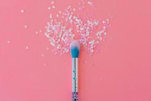 Makeup brush and shiny pink sequins on a pink background. Festive magic makeup concept. Template for design, top view Flat Lay Copy space. photo