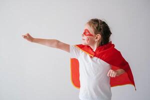 Funny little super hero girl in a red cloak. Superhero concept. Little child playing hero in the kids photo