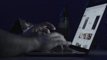 giovane uomo Lavorando su computer a notte nel buio camera. il progettista lavori nel il dopo volta. uomo Lavorando su il computer portatile nel il buio video