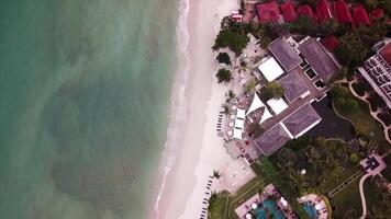 oben Aussicht von schwarz vulkanisch Strand mit Wellen von Ozean auf sauber Ufer mit Häuser zum Sommer- Urlaub. Video. Antenne Landschaft Schießen von schön Meer mit azurblau Wasser und Wellen video