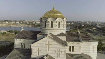 hermosa ver de grande ruso templo en río banco cerca el ciudad. disparo. ver de el blanco Iglesia con dorado domos en el río banco en contra el ciudad. video