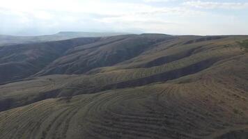 Aerial view of agricultural fields in the mountains with blue sky background. Shot video