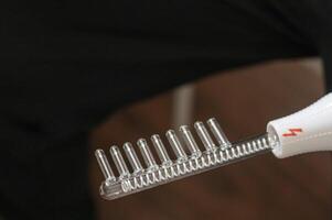 Close up shot of the high frequency comb tool for hair and scalp treatment. Healthcare photo