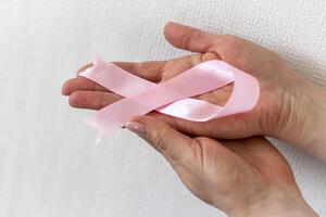 Shot of a woman holding pink ribbon, symbol of a breast cancer awareness. Concept photo