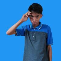 Confused Asian young man blue t-shirt, isolated blue background photo