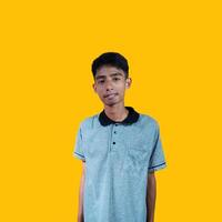 serious young asian man wearing gray t-shirt, isolated yellow background. photo