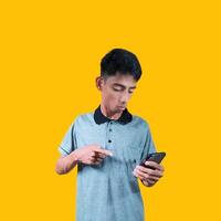 excited young man holding a smart phone wearing a gray t-shirt, yellow background. photo