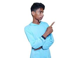 excited asian man wearing blue t-shirt pointing to the copy space on the side, isolated white background. photo