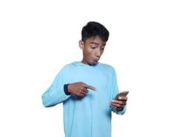 Young asian man surprised looking at smart phone, wearing blue t-shirt, isolated white background. photo