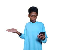 Excited Asian man wearing blue t-shirt pointing at copy space, white background. photo