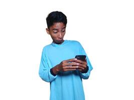 Young asian man surprised looking at smart phone, wearing blue t-shirt, isolated white background. photo