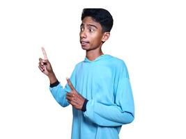 excited asian man wearing blue t-shirt pointing to the copy space on the side, isolated white background. photo