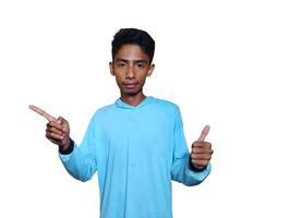 excited asian man wearing blue t-shirt pointing to the copy space on the side, isolated white background. photo