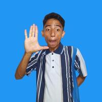 young asian man dressed in colorful t-shirt raising arms saying hay meet friends isolated blue background. photo