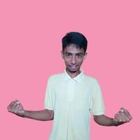 el entusiasta cara de el asiático juventud apretado su puños aislado en rosado antecedentes. foto