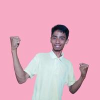 The enthusiastic face of the Asian youth clenched his fists. isolated on pink background. photo