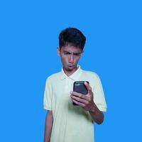 Young Asian man surprised looking at smart phone screen, purple background. photo